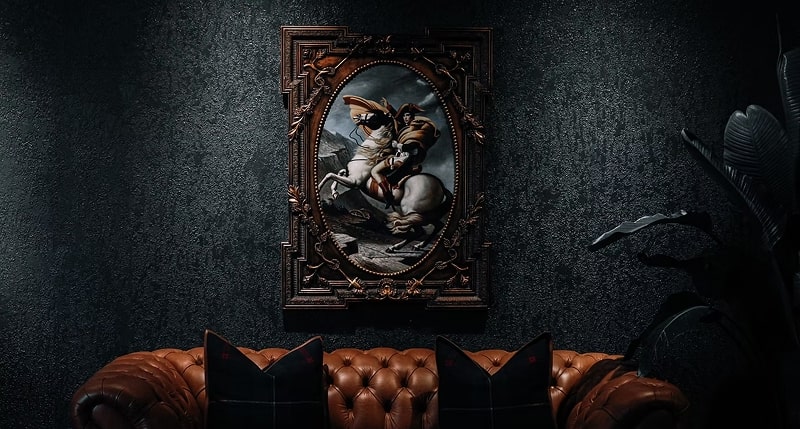 Elegant oil painting in an ornate frame above a brown leather couch.